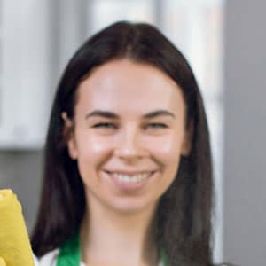 A woman holding a yellow cleaning sponge while repairing a tablet.